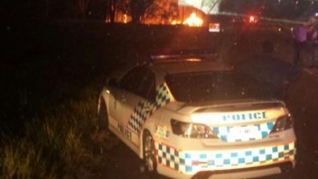 Police look on as a 4WD and police car burn following a police chase through Brisbane's north that ended at Deagon.