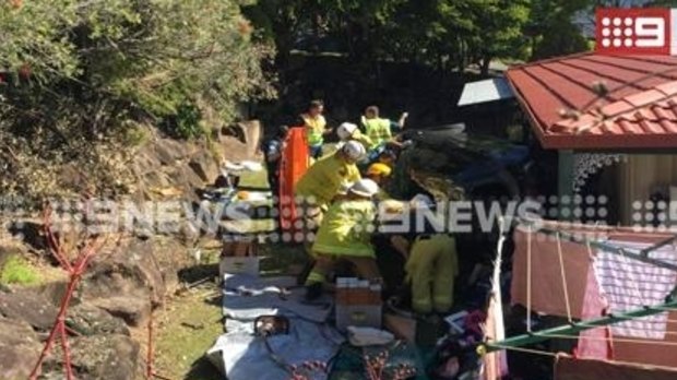 Emergency crews work to free a woman from a car that ran off the road at Molendinar on the Gold Coast.