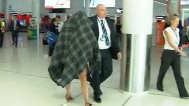 Police escort the accused transgender prostitute from Perth Airport.