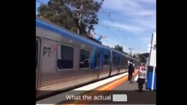 A video shows two people train surfing on top of a Metro train.