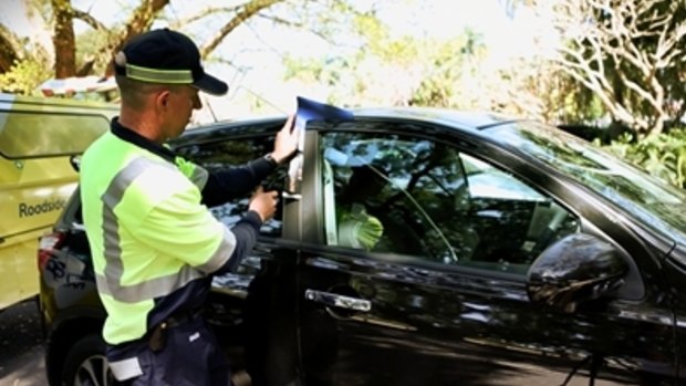 An RACQ road service crew worker opens a locked car.