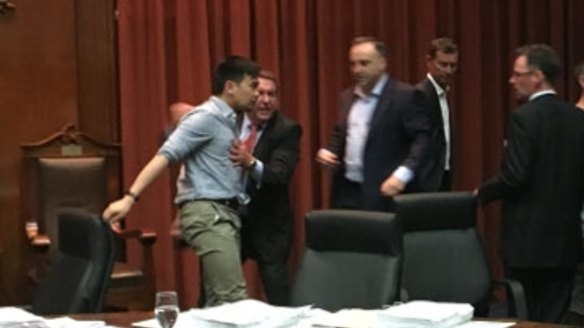 Councillor Nam Quach is helped to his feet after the meeting erupted into a brawl over parking meters.