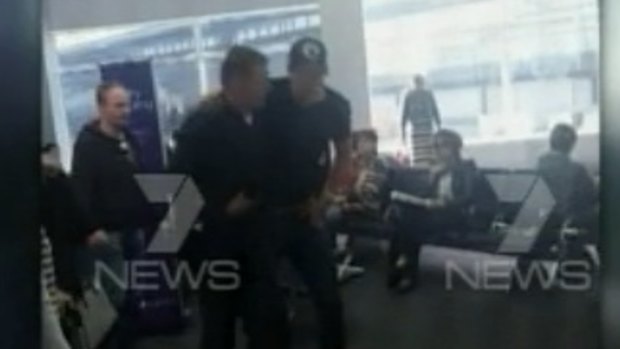 Grant Hackett is helped by a fellow passenger after the flight from Adelaide to Melbourne.