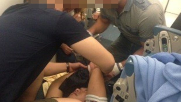 An agitated passenger is restrained after trying to open the emergency exit on a Vietnam Airlines flight to Sydney. 