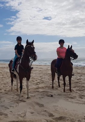 Trip of a lifetime: Olivia, left, and sister Jamie Hewitt-Toms ride their horses at Cabarita Beach, NSW.