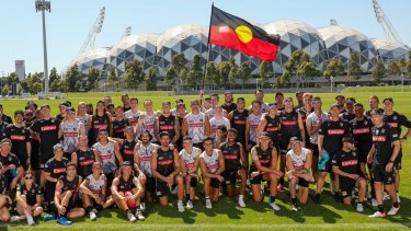 Collingwood players and staff with the Aboriginal flag.