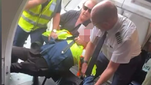 A still from footage of the boy being restrained by a Jetstar worker, passenger Barry Clark and the pilot.