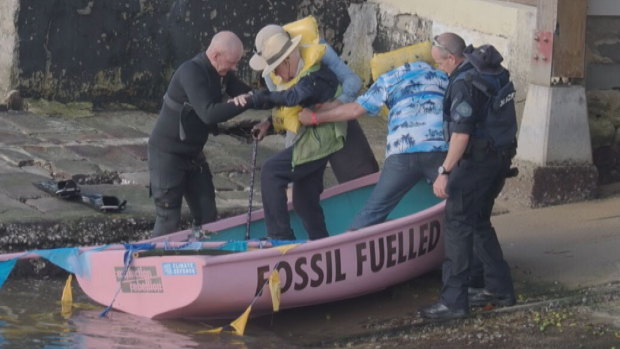 Reverend Alan Stuart is assisted by police out of a boat.
