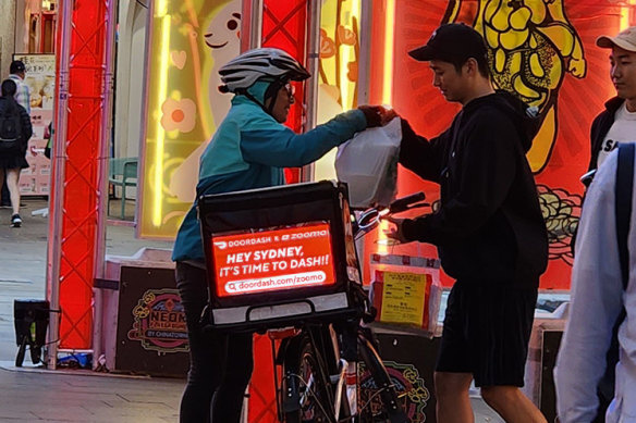 A delivery rider drops off food using a Lumos bag.