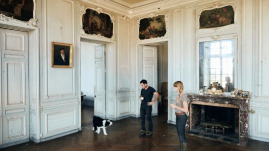 Tim Holding with his fiancée, Felicity Selkirk, and dog Truffe outside their 105-room 
fixer-upper.