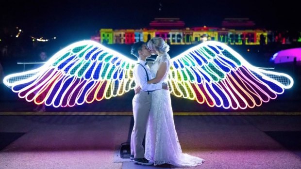 Mhera Nelson-Insch and Bella Insch snuck out of their wedding at the NGA to grab a memorable photo at the Neon Angel Wings installation at Enlighten.