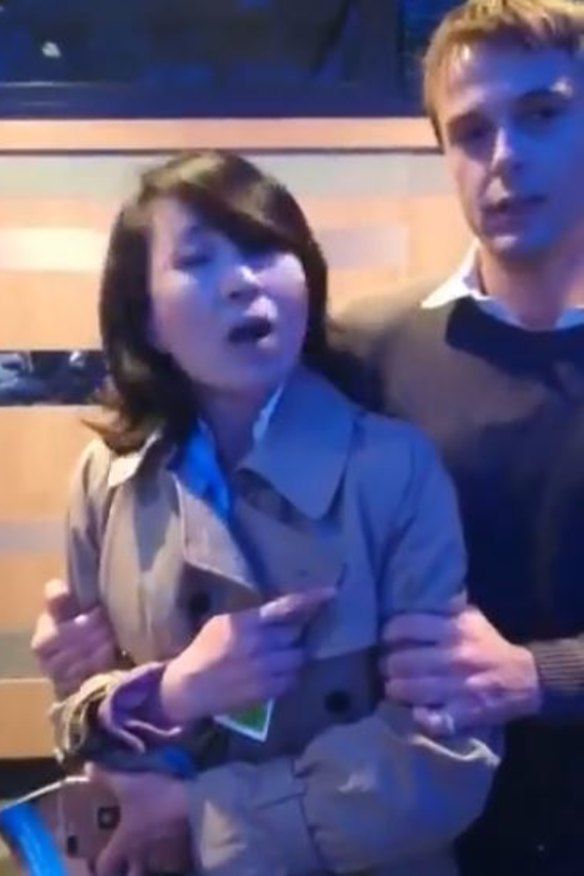 The reporter is restrained by an organiser after slapping another.