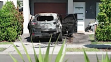 The charred shell of an SUV was seen in the driveway of the Moorebank home following the attack.