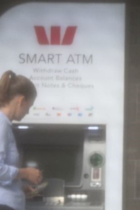 Mr Woodman's assistant takes cash out of an ATM.