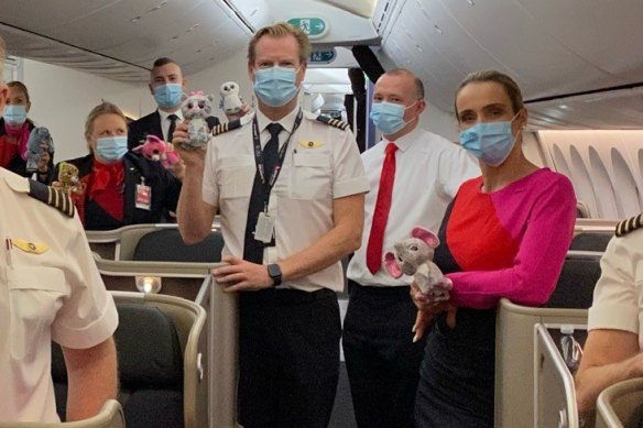 Flight attendant Claudine Peats, far left at back, and Captain Phil Paterson, centre, with some soft toys his wife packed for Afghan refugee children on a recent flight to Australia. 
