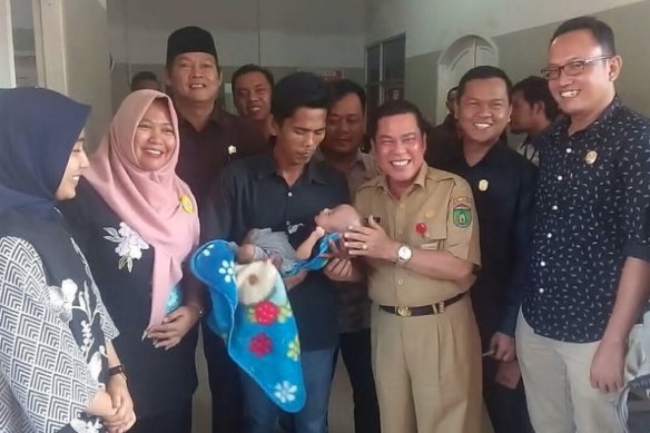 Baby Delfa Barki Abbasi and his father Father Febrianto, centre, were reunited after a controversy that caputred the attention of Indonesians.