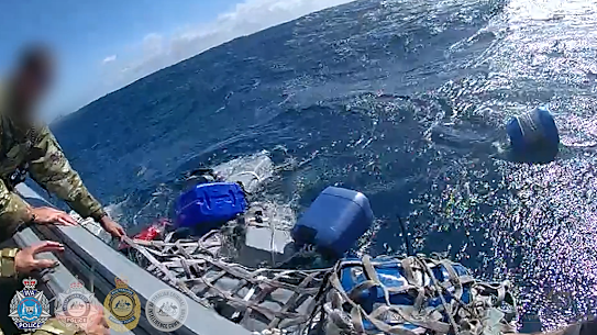 Officers pull the cocaine blocks aboard.
