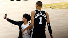 A fan runs onto the court and takes a photo with Victor Wembanyama.