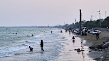 People swim and spend time along the shore of the Strait of Hormuz.