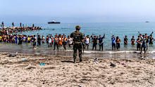 Spanish army soldiers block access to the beach for people crossing from Morocco into the Spanish enclave of Ceuta.