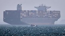 A container ship sits at anchor as a small motorboat passes in the foreground in the Strait of Hormuz off Bandar Abbas, Iran, Saturday, May 2, 2026