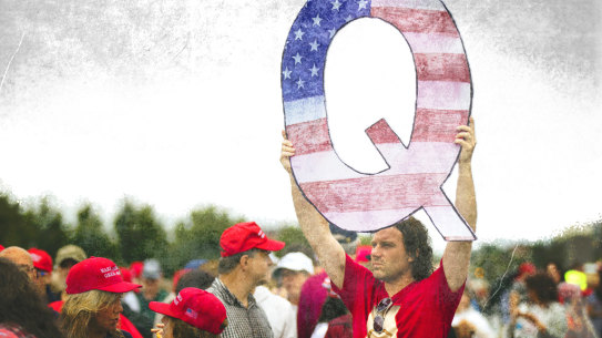 A Donald Trump supporter holds up a QAnon sign at a rally in 2018. 