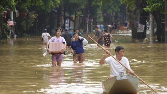 People carrying belongings wade in a flooded street in the aftermath of Typhoon Yagi in Hanoi, Vietnam.