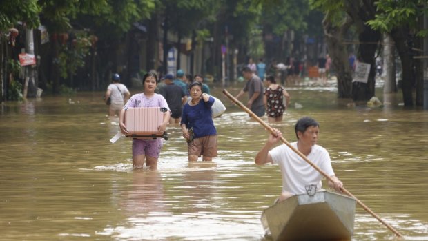 People carrying belongings wade in a flooded street in the aftermath of Typhoon Yagi in Hanoi, Vietnam.