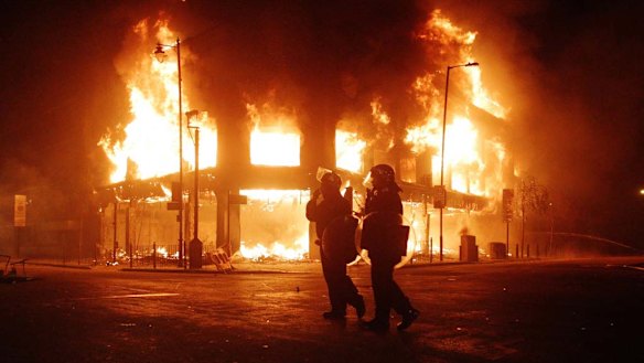 Riot police look on as fire rages through a building in Tottenham, north London, during the 2011 riots.