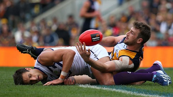 Eric Mackenzie of the Eagles tackles Matthew Pavlich of the Dockers after a marking contest.