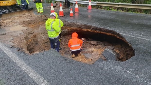 Workers assess the damage to The Wool Road at Old Erowal Bay from the pothole that opened up this month.