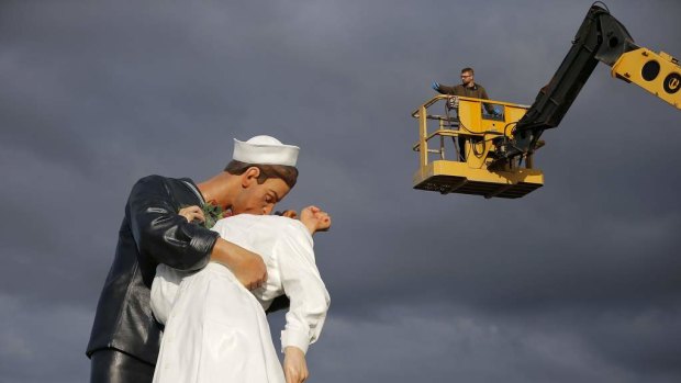 A worker takes a picture of the "Unconditional Surrender" sculpture by artist Seward Johnson during its installation outside the Memorial of Caen museum in Caen.