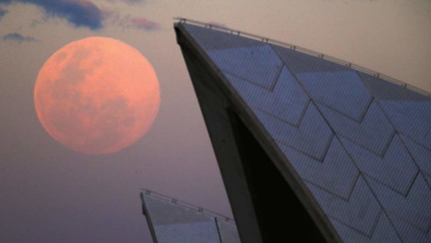 A supermoon rises behind the roof of the Sydney Opera House.