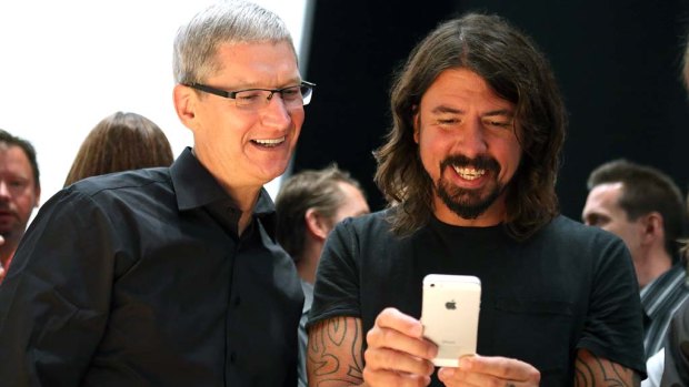 Apple CEO Tim Cook, left, and Dave Grohl of the Foo Fighters play with the iPhone 5.