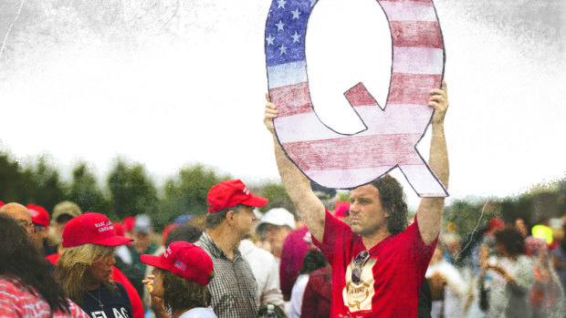 A Donald Trump supporter holds up a QAnon sign at a rally in 2018. 
