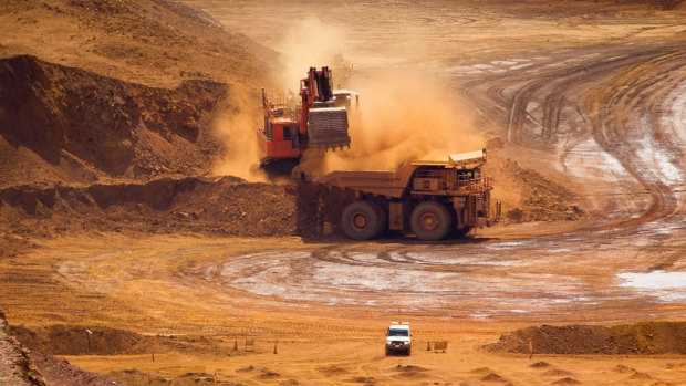 A haul truck is loaded by a digger with material in the pit at one of Rio Tinto's Pilbara iron ore mines.