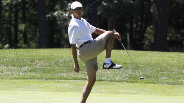 President Barack Obama reacts as he misses a shot while golfing.