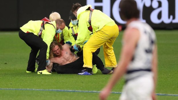 Optus Stadium security subdue the pitch invader, who faces a $50,000 fine.