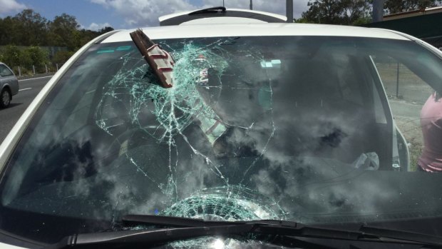 A woman has escaped without injury after a plate has smashed through the windscreen of her car in Queensland.