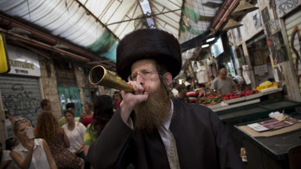An Ultra-orthodox Jewish man blows a trumpet to announce the starting of the Sabbath, Judaism's biblically mandated day of rest, at the Mahane Yehuda market in Jerusalem.