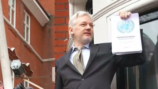 Julian Assange brandishes a 2016 UN report that found he was being detained unlawfully.