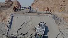 An overturned car sits on a section of a destroyed bridge after a strike in southern Iran.
