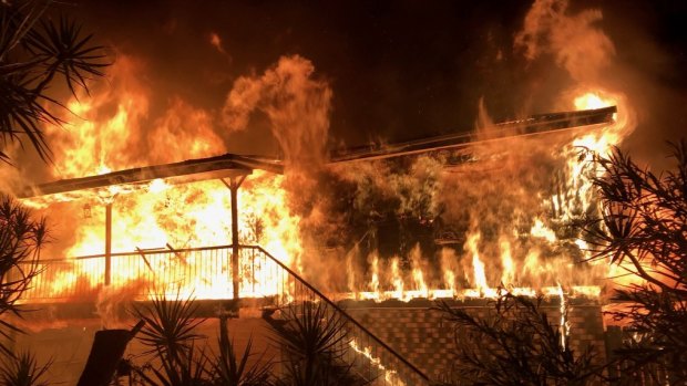 The two-storey Crestmead home is engulfed by flames.
