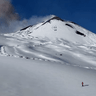 Skier comes down Mount Etna as volcano erupts in the background