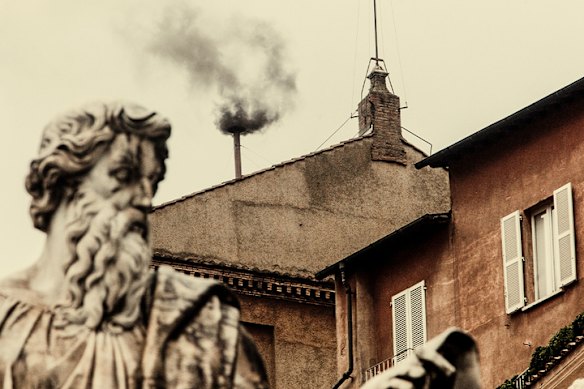 Black smoke billows from a chimney in the Sistine Chapel, indicating that a new pope has not been chosen yet. Tens of thousands of Catholics keep a vigil, waiting for the smoke to turn white.