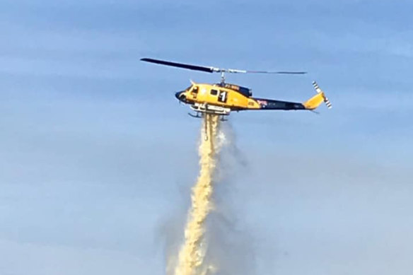 A stock image of a helicopter dumping water near a Tasmanian fire in 2020.