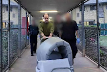 Pushing his bedding under the watchful eye of prison guards, a convicted monster on the move.