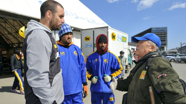 Pitching in: Scott Fardy and Seawaves teammates Lata Lui and Pita Alatini talk with their friend Kenji Sano, a 79-year-old liquor shop owner, as they volunteer to deliver emergency aid at a makeshift logistics center in Kamaishi in March 2011. 