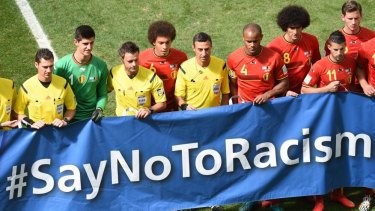 Belgium and Argentine players and referees pose with a "Say No to Racism" banner during a quarter-final football match.