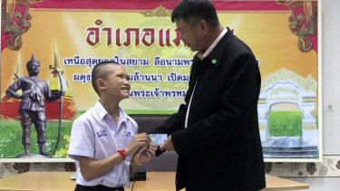 Mongkol "Mark" Boonpiam, 14, left, receives an identity card denoting Thai citizenship from Mae Sai Sheriff Somsak Kunkam during a ceremony in Mae Sai on Wednesday.